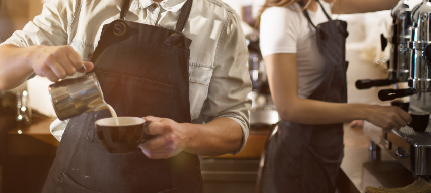 Barista’s Making coffee next to an industrial size coffee machine